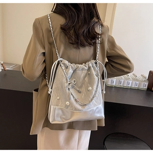 Silver drawstring bucket backpack with metallic texture and large pearl accents