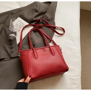 Detailed shot of dark red litchi grain leather tote bag with silver metal accents