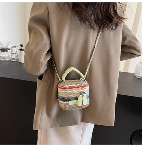 Detail of colorful mini straw crossbody bag with metal chain strap worn by a model