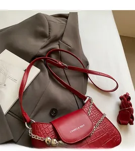 Detail of red crocodile texture handbag with silver chain strap and adjustable leather strap