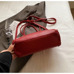 Macro detail of red litchi texture tote bag with silver hardware and adjustable strap