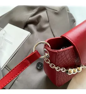 Close-up of red crocodile-embossed leather texture and silver chain with metal beads