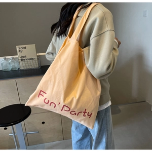 Sac fourre-tout en toile abricot avec imprimé Fun Party rouge porté à l'épaule