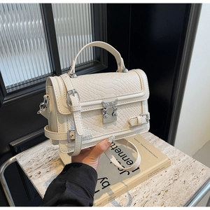 Detailed view of cream crocodile embossed crossbody bag with silver clasp and top handle