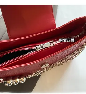Detailed close-up of smooth silver zipper and red croc-embossed leather texture