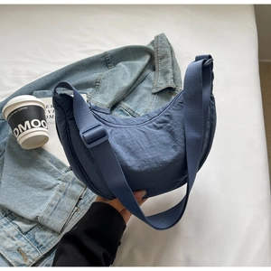 Détail du sac demi-lune en nylon bleu avec bandoulière réglable et tissu texturé