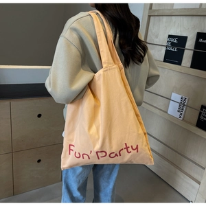 Vue latérale d'un grand sac fourre-tout en toile pêche avec texte Fun Party rouge