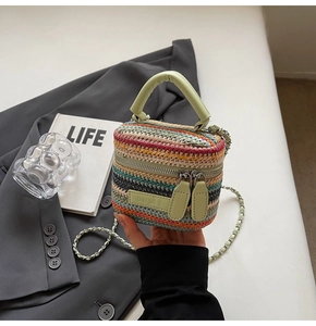 Detailed view of mini woven bag with colorful stripes, green leather handle and chain strap