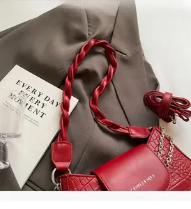 Detail of red crocodile texture handbag with woven handle on a gray blazer backdrop