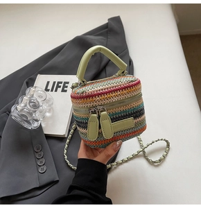 Detail of colorful woven straw mini bag featuring green leather trim and gold chain strap