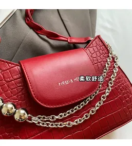 Detail of red crocodile texture handbag with silver chain and decorative metal spheres
