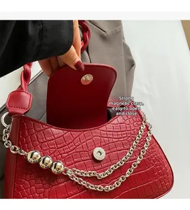 Close-up of red crocodile embossed shoulder bag featuring a strong magnetic snap closure