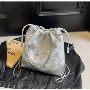 Detail of silver drawstring bucket bag with pearls, rhinestone bow and chain strap