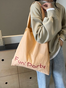 Grand sac cabas en toile beige avec imprimé Fun Party porté en bandoulière par un mannequin