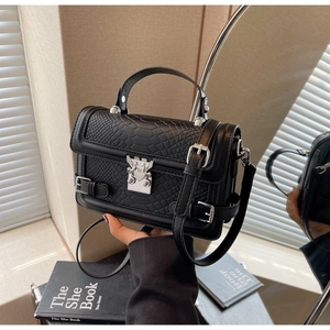 Detail of black faux crocodile skin bag featuring silver angel buckle and smooth top handle