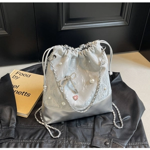 Detail of silver bucket bag with pearls, diamond bow, and metal chain strap