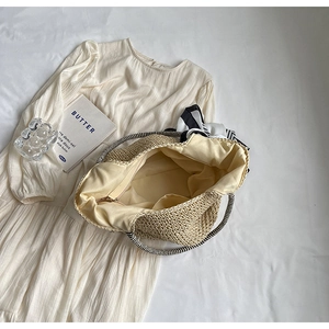 Internal view of straw tote bag showing beige fabric lining and zipper inner pocket