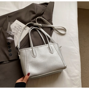 Detail of silver lychee texture leather tote bag with silver hardware and shoulder strap