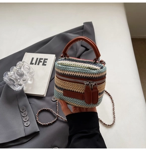 Detail of multi-color woven straw mini bag with brown leather handle and chain strap