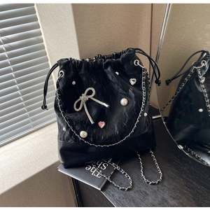 Detail of black drawstring bucket bag with pearl heart and bow charm decorations