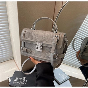 Detail of grey crocodile embossed handbag with premium metal buckle and handle
