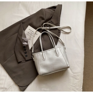 Close-up of silver lychee texture tote bag with cylindrical handles and adjustable strap