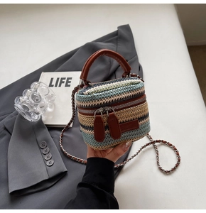 Detail of color-block striped woven mini bag with leather handle and metal chain strap