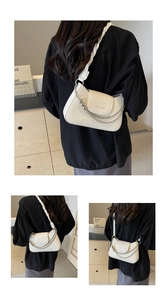 Macro shot of white crocodile embossed shoulder bag with gold chain and woven strap