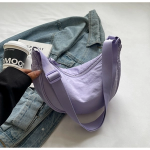 Détail du sac demi-lune en nylon violet avec bandoulière sur fond décontracté