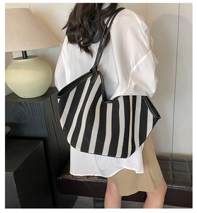 Close-up of a large striped tote bag featuring mesh texture and black leather straps