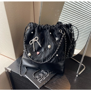 Detail view of bucket backpack with pearls, rhinestone bow, and silver chain strap