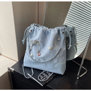 Close-up of light blue satin bucket bag with rhinestone bow and pearl decorations