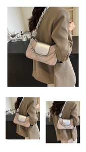Detail of beige crocodile pattern handbag with silver metallic flap and thick woven strap