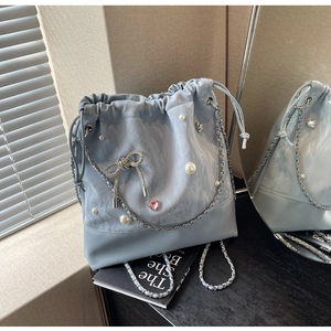 Close-up of light blue bucket bag with pearls, rhinestone bow, and metallic chain detail