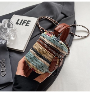 Macro view of multi-color woven cylinder straw bag with leather handle and chain