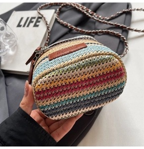 Close-up of a mini multicolored straw woven bag with a branded leather tag and metal chain
