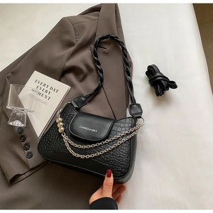 Detail of black crocodile texture bag with silver chain and twisted woven handle strap
