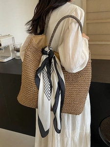 Large straw tote bag with striped handles and decorative scarf for summer travel