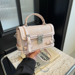 Pink crocodile-embossed crossbody bag with silver wing clasp and marble background