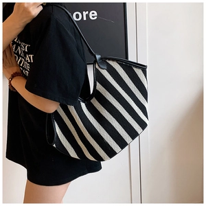Primer plano de un gran bolso tote a rayas blancas y negras con ribetes de cuero