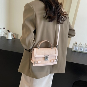 Pale pink croc-textured crossbody bag with silver buckle and top handle shown on model
