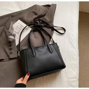 Detailed view of black lychee-textured leather tote bag with adjustable shoulder strap