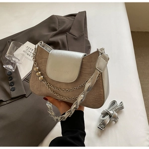 Detail of beige crocodile texture bag with silver chain and brand logo engraving