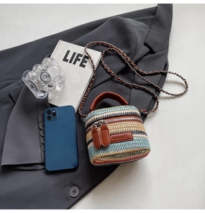 Detailed flatlay of a colorful mini straw bucket bag with a chain strap and leather handle