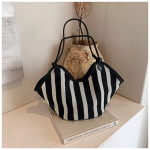 Primer plano de un bolso tote de rayas en forma de abanico sobre libros de decoración