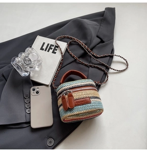 Detail of colorful woven mini bucket bag with leather handles and chain strap
