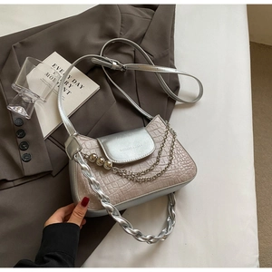 Detailed view of silver crocodile embossed handbag with metal ball chain and woven strap