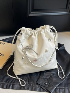 Chic cream white drawstring bucket bag with pearl accents and sparkling diamond bow detail