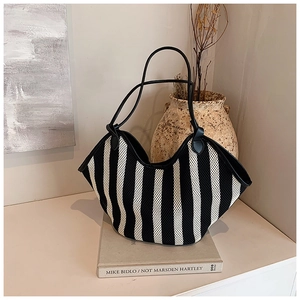 Detalle del bolso tote tejido a rayas blancas y negras con asas largas de cuero