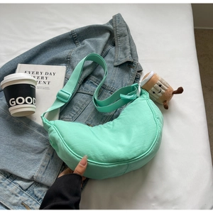 Détail du sac croissant en nylon vert menthe avec bandoulière et breloque café en peluche